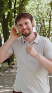 Sporcu spor koşucusu maraton koşusu yapıyor, kulaklıkla müzik dinliyor. Sabah parkta kardiyo çalışması var. Sağlıklı yaşam tarzını seven mutlu genç bir adam. Aktif sporcu koşucu.