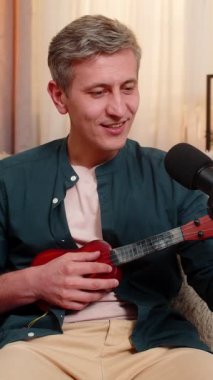 Evdeki genç blogcu neşeli bir şekilde kanepede ukulele çalar, duygusal ve eğlenceli bir şekilde şarkı söyler. Gri saçlı adam stüdyo mikrofonunda müzik kaydediyor, yaratıcılık, tutku, yetenek ve stil ifade ediyor..