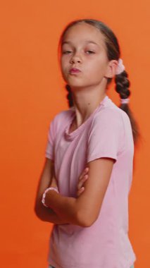 Neşeli, komik, genç liseli kız kameraya dil gösteriyor, dalga geçiyor, şakalaşıyor, zorbalıkla dalga geçiyor. Turuncu arka planda 10 yaşında çocuk.