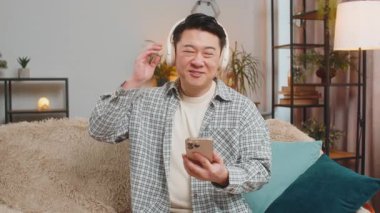 Aşırı mutlu, orta yaşlı, kablosuz kulaklık takan, koltukta oturup telefonla en sevilen disko dansını dinleyen adam. İnsanlar hafta sonu boş zaman aktiviteleri.