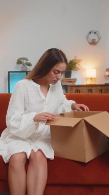 Memnun olmayan bayan müşteri karton kutu açıyor. Kablosuz kulaklıklar zarar görüyor. Genç bir kadının eve kötü sipariş teslimatıyla ilgili şikayeti var. Dikey