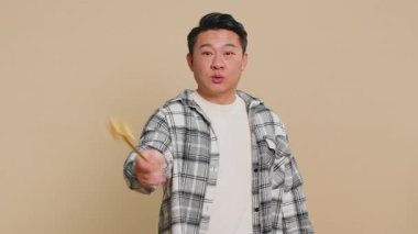 Sihirbaz cadı Asyalı orta yaşlı adam sihirli değnek ve sihirli değnekle el kol hareketi yapıyor, dilekleri gerçekleştiriyor, sihirbazlık büyüsü yapıyor, tatil indirimi yapıyor. Bej arka planda olgun Çinli bir adam.