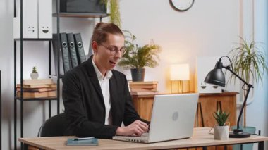 Dizüstü bilgisayar ağı üzerinde çalışan genç beyaz iş adamı ani iyi kariyer haberleri, zafer, galibiyet, gol başarısı karşısında şok oldu. İş yerinde yumruklarını sıkan heyecanlı, serbest çalışan adam..