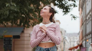 Düşünceli gülümseyen, düşünceli, mutlu, genç, yetişkin bir kadın. Çözüm üzerinde kafa yoran, soru soran, ilham veren açık havada rüya gören. Şehir sokağındaki güzel kız. Kasaba yaşam tarzları.