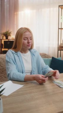 Genç bir kadın nakit parayı evde ayırıyor, porsiyonları biraz tereddüt ve belirsizlikle ayırıyor. Kız dolar banknotlarını zarfa atar, mali yükümlülükler planlar, gelecekteki harcamalar.