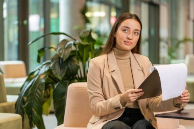 Belgelerle çalışan, bilgi okuyan, gazete okuyan, finansal rapor hazırlayan Kafkasyalı genç iş kadını. Genç bayan girişimci ofis lobisindeki grafik belgelerini analiz ediyor.