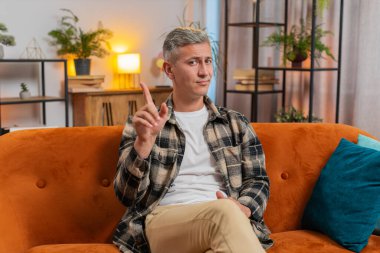 Gri saçlı hoşnutsuz, berbat bir fikre tepki veren mutsuz bir adam kötü kalite el sıkışmasından memnun olmayan bir adam. Genç adam kanepede oturuyor.