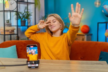 Kafkasyalı genç çocuk evdeki akıllı telefondan son moda selfie videosunu kaydediyor. Dans hareketleri göstermek, masa masa oturmak, sosyal medya için coşkuyla içerik yaratmak.