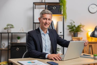 Resmi takım elbiseli genç, gri saçlı işadamı dizüstü bilgisayarı açıyor mesajlar gönderiyor, filmler izliyor, online alışverişler yapıyor. Modern ofis çalışma alanında netbook kullanan beyaz bir adam..