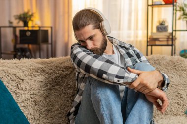 Genç adam evde oturup kulaklık takıyor, duygusal melodiler dinliyor, göz yaşlarına karşı savaşıyor. Kanepedeki adam kulaklıkları çıkarıp acı dolu ayrılık ya da ayrılık üzerine derin bir iç çekiş veriyor. Kırık kalp
