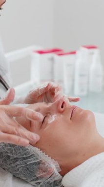 Deneyimli bir terapist kadına elleriyle masaj yaptırıyor. Salonda pürüzsüz, sağlıklı cilt bakımı. Göz altı torbaları iyileşiyor. Yüz fiziksel kozmetoloji oturumunda genç bir müşteri