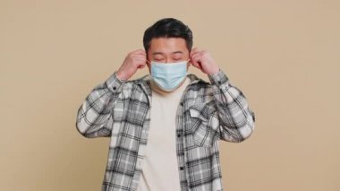 Asyalı orta yaşlı adam mutlu bir şekilde çıkartıyor, tıbbi maskesini çıkarıyor ve atıyor. Grip tedavisi. Bulaşıcı hastalıklardan sonra karantina sona eriyor. Bej arka plandaki Çinli adam.