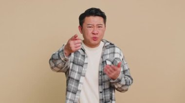 Sen delisin, aklın yerinde değil. Kafası karışmış orta yaşlı Asyalı bir adam kamerayı işaret edip aptalca bir jest yapıyor, aptalın birinden delice bir plan yapmasını istiyor, zorbalık yapıyor. Bej arka planda olgun Çinli bir adam.