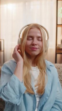 Gün batımında evde müzik dinleyen genç bir kadın, gözleri yavaşça hareket eden ve kurnaz bir gülümsemeyle kapatıyordu. Kanepedeki beyaz kız melodiyi huzurlu bir duruşla hissediyor, neşe ve duygusal rahatlamayı yansıtıyor.