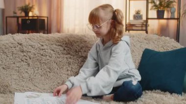 Genç kız evde oturuyor, yüzüne büyük gözlük takıyor ve yavaşça başını sallayarak yetişkin gibi davranıyor. Ciddi bir ifadeyle kanepede oturan sarışın çocuk, evrak ve makbuz okuyor, kendini komik hissediyor.