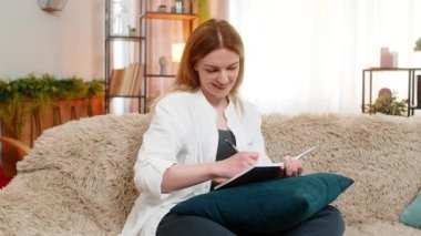 Orta yaşlı bir kadın elinde kalemle kanepede çizim yapıyor. Düşünceli bir ruh hali ve ilham veriyor. Genç yetişkin bir kız yaratıcı akışı ve sanatsal anı yansıtan odaklanmış bir şekilde yaratıyor.