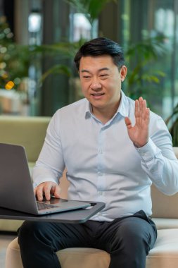 Modern ofis lobisinde dizüstü bilgisayarda çalışan kendine güvenen bir iş adamı çalışanla online iletişim videosu konuşması yapıyor, patron. Tişört destek servisinde yönetici bilgisayarın webcam 'ine bakıyor