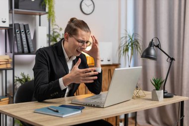 Genç, üzgün, stil sahibi bir iş adamı dizüstü bilgisayarda arama yapıyor, beklenmedik piyango sonuçlarını kaybediyor, servet kaybı, ofis masasında kötü haberler. Takım elbiseli, Kafkasyalı serbest çalışan.