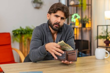 Evdeki Hintli adam cüzdanı açar. Sadece bozuk paraları bulur. Borçları ve gecikmiş faturaları düşünür. Masa başı bütçesindeki Arap adam para sayıyor. Küçük gelir notları, okuma ücretleri, harcamaları azaltıyor.