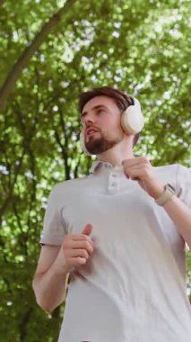 Sportif fitness sporu koşucusunun altında maraton koşucusu, kulaklıkla müzik dinliyor. Sabah parkta kardiyo çalışacaksın. Genç adam sağlıklı yaşam tarzını seviyor. Aktif sporcu koşucu.