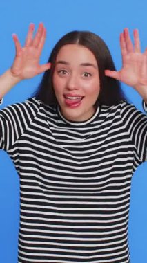 Komik beyaz kadın kameraya dil gösteriyor, dalga geçiyor, şakalaşıyor, alay ediyor, alay ediyor, alay ediyor, kabadayılık ediyor, saygısızlık ediyor. Güzel genç kız mavi arka planda izole edilmiş.