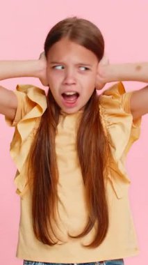 Genç kız iki eliyle kulaklarını kapatıyor, yüksek bir ses ya da gürültüden kaynaklanan ani korku paniğiyle gözlerini ardına kadar açıyor. Pembe arka planda izole edilmiş bir okul çocuğu duygusal bir jest yaparak tepki veriyor.