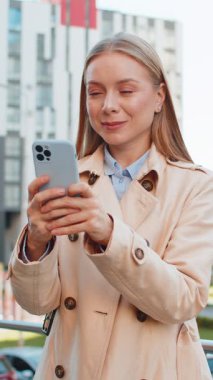 Kafkasyalı yetişkin bir iş kadını cep telefonuyla internette sohbet ediyor mutlu bir orta yaşlı kadın cep telefonu kullanıyor, şehir merkezindeki caddede SMS ile iletişim kuruyor..