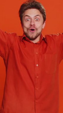 Sihirbaz, sihirli değnek ve sihirli değnekle el kol hareketi yapan yakışıklı adam dileği gerçekleştiren sihirbaz reklam indirimi yapıyor. Kafkas sakallı adam turuncu arka planda izole edilmiş.