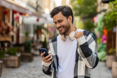 Cep telefonu kutlaması yapan Hintli genç adam iyi haber kazandı, piyango büyük ikramiyesi kazandı, açık havada dağıttı. Şehir caddesinde İspanyol bir gezgin. Kasaba yaşam tarzları.