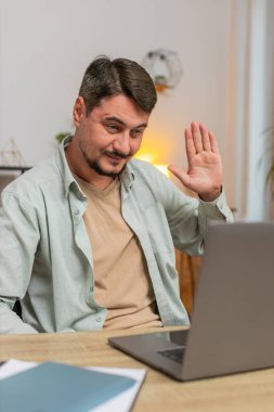 Ev ofisinin bilgisayarında çalışan mutlu serbest çalışan bir adam çalışanlarıyla online iletişim videosu konuşması yapıyor, patron. Yönetici destek servisi bilgisayarın webcam 'ine bakıyor. Dikey.