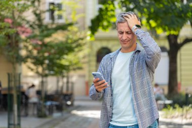 Akıllı telefon daktilosu kullanan olgun, gri saçlı bir adam aniden piyango sonuçlarını, kötü haberi, servet kaybını ve başarısızlığı kaybediyor. Şehir caddesinde duran bir turist. Kasaba yaşam tarzları.