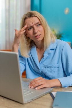 Baş ağrısı, gerginlik, migren, iş yerindeki stresten muzdarip yorgun genç iş kadını. Dizüstü bilgisayarla çalışan sarışın, serbest çalışan kadın. Fazla çalışma.