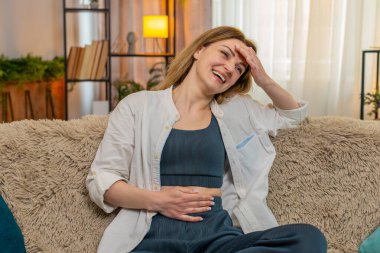 Orta yaşlı, mutlu bir kadın evinde kanepesinde kendi kendine güler ve güler. Komik bir şey hatırlar. Genç yetişkin kız neşeli duyguları ve kişisel mutluluğu neşeli, samimi bir yansımayla kucaklıyor..