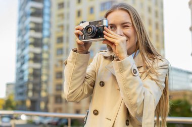 Hafta sonları şehir keşfi yapan orta yaşlı mutlu kadın turist dışarıda antika kameralarda fotoğraf çekiyor. Şehir sokağında tatilde uzun paltolu bir kız. Yaşam Tarzları.