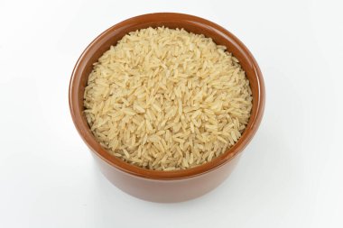 Beyaz arka planda bir kasede çiğ kahverengi pirinç.