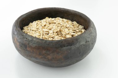 Beyaz arka planda, kırsal bir kasede çiğ yulaf ezmesi.