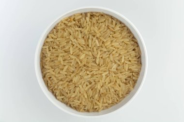 Beyaz arka plan görünümlü bir kasede çiğ kahverengi pirinç.