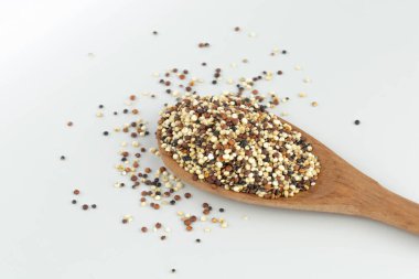 Beyaz arka planda ahşap kaşıkta kinoa tohumu karışımı izole edilmiş.