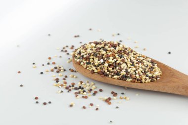 Beyaz arka planda ahşap kaşıkta kinoa tohumu karışımı izole edilmiş.