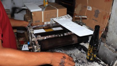 Workers making white license plates for a new type of motor vehicle, Pekalongan, Indonesia, October 17, 2022