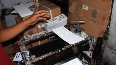 Workers making white license plates for a new type of motor vehicle, Pekalongan, Indonesia, October 17, 2022