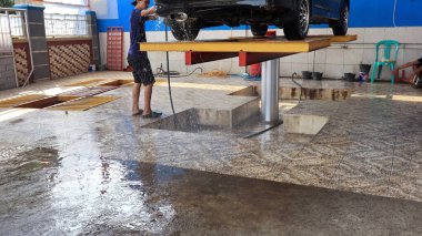 Worker car cleaning, spraying and wiping, clean the car from dirt, at his workplace, Batang, January 16, 2023