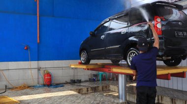 Worker car cleaning, spraying and wiping, clean the car from dirt, at his workplace, Batang, January 16, 2023