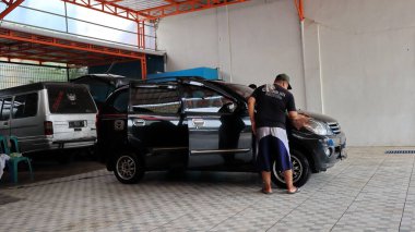 Worker car cleaning, spraying and wiping, clean the car from dirt, at his workplace, Batang, January 16, 2023