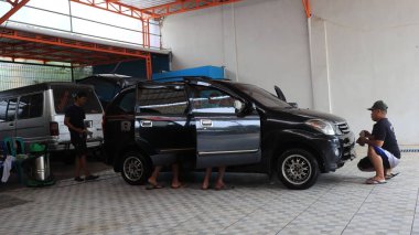 Worker car cleaning, spraying and wiping, clean the car from dirt, at his workplace, Batang, January 16, 2023