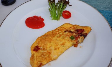 Omelet served with vegetables and spicy sauce