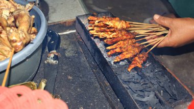 The process of burning satay on the burning coals. satay on fire with smoke and an appetizing look. hands cooking satay on the grill