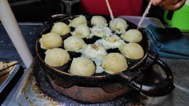 Geleneksel gece pazarında takoyaki pişirme süreci.