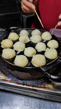 Geleneksel gece pazarında takoyaki pişirme süreci.