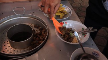 Bir soto lamongan satıcısı, 8 Ocak 2023 'te tezgahında bir menü hazırlıyor, Batang Endonezya.